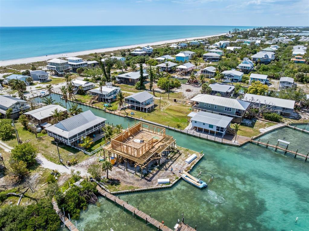 An aerial view shows a coastal neighborhood with a house under construction on stilts — 9750 LITTLE GASPARILLA ISLAND, BOCA GRANDE, FL