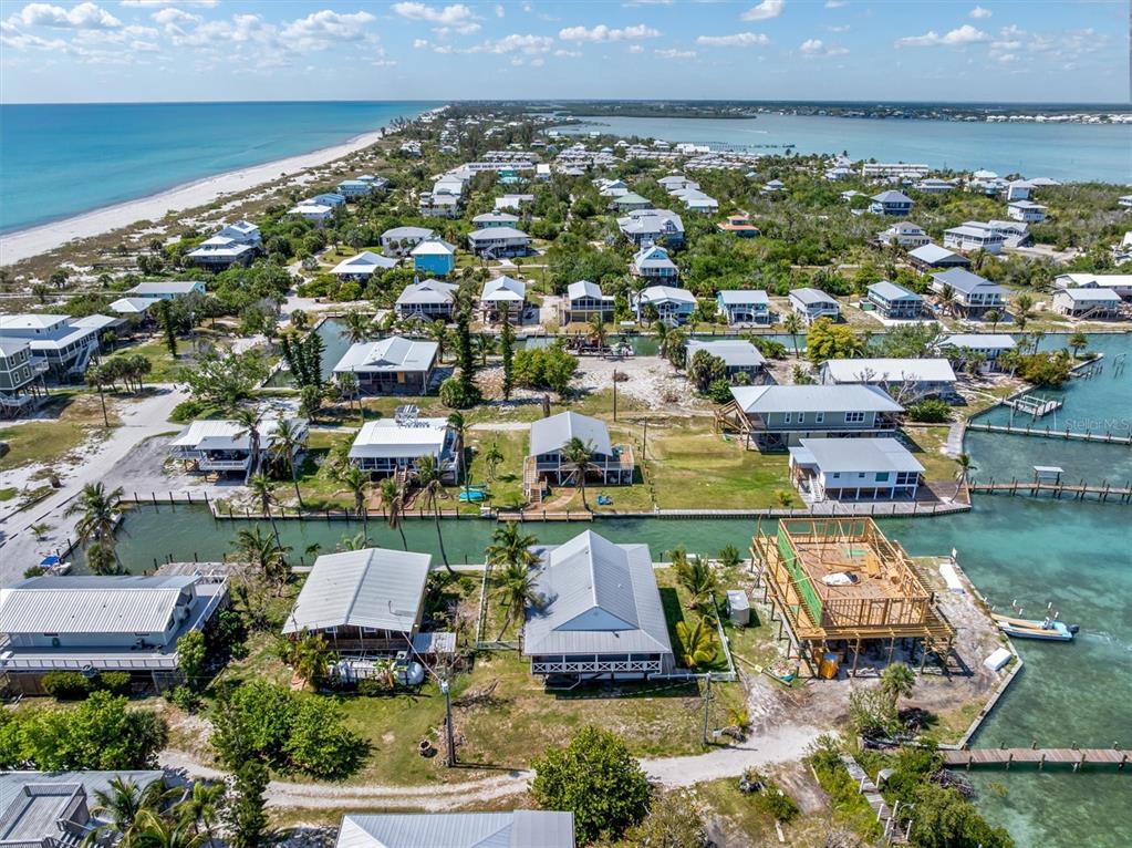 An aerial view shows waterfront houses with docks along a canal near the beach — 9750 LITTLE GASPARILLA ISLAND, BOCA GRANDE, FL