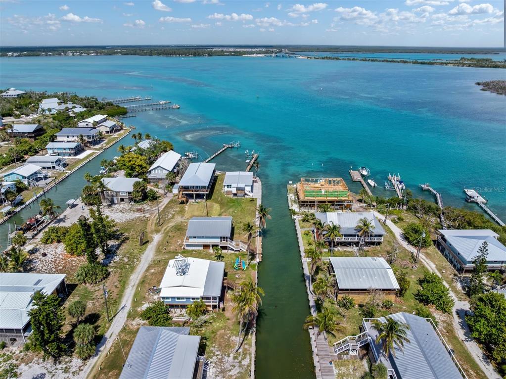 An aerial view shows waterfront homes along a canal leading into a large bay — 9750 LITTLE GASPARILLA ISLAND, BOCA GRANDE, FL
