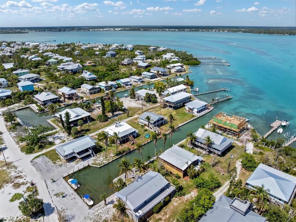 An aerial view shows a coastal neighborhood with houses along a canal and the ocean — 9750 LITTLE GASPARILLA ISLAND, BOCA GRANDE, FL
