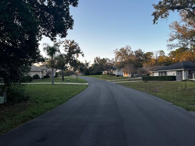 A paved road curves through a residential neighborhood with houses, trees, and grassy lawns — 1 GRAYTWIG COURT W, HOMOSASSA, FL