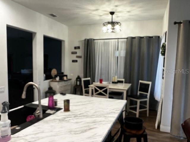 A kitchen island with a marble countertop overlooks a dining area with a chandelier — 1 GRAYTWIG COURT W, HOMOSASSA, FL
