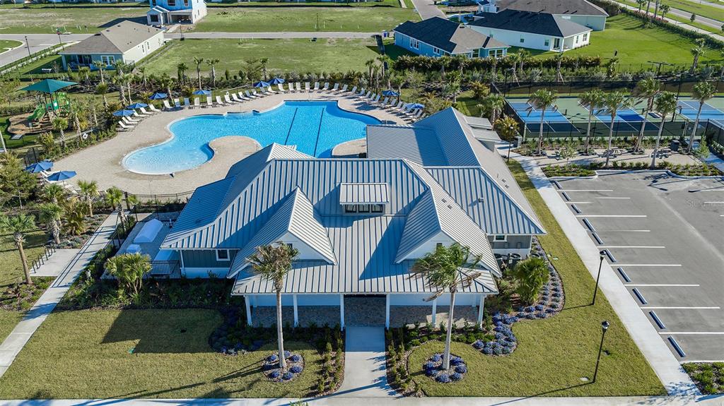 An aerial view shows a community clubhouse with a metal roof, pool, and tennis courts — 5086 CHAPEL ROW AVENUE, APOLLO BEACH, FL