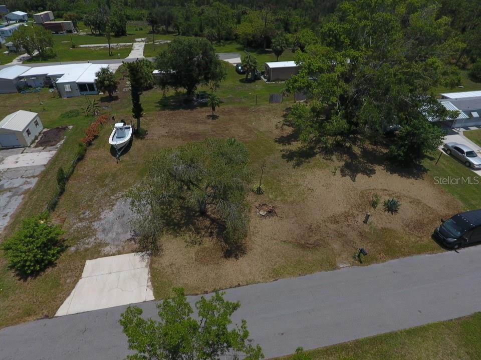 An aerial view shows a vacant, grassy residential lot with trees and a parked boat — 3825 BRAVO ROAD, PORT CHARLOTTE, FL