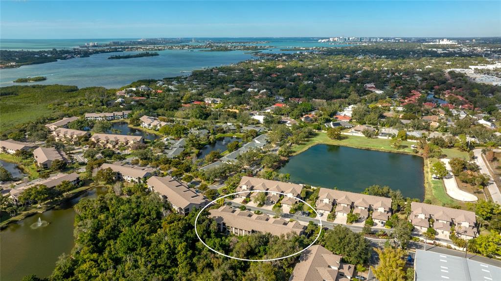 An aerial view shows a residential complex with multiple buildings, a lake, and surrounding greenery — 1648 STARLING DRIVE UNIT 202, SARASOTA, FL