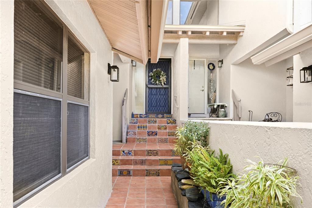 An outdoor entryway features tiled stairs with decorative risers leading to a front door — 1648 STARLING DRIVE UNIT 202, SARASOTA, FL