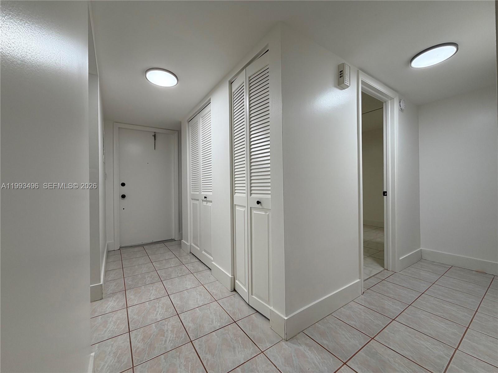 A hallway features white louvered closet doors, tiled flooring, and two circular ceiling lights — 400 Commodore Dr # 101, Plantation FL 33325, PLANTATION, FL