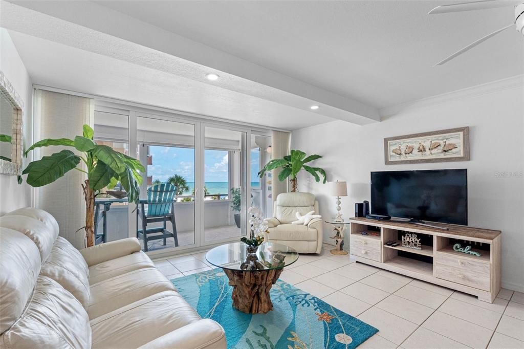 A living room features a white sofa, glass-topped coffee table, and sliding doors to a balcony — 17920 GULF BOULEVARD UNIT 302, REDINGTON SHORES, FL