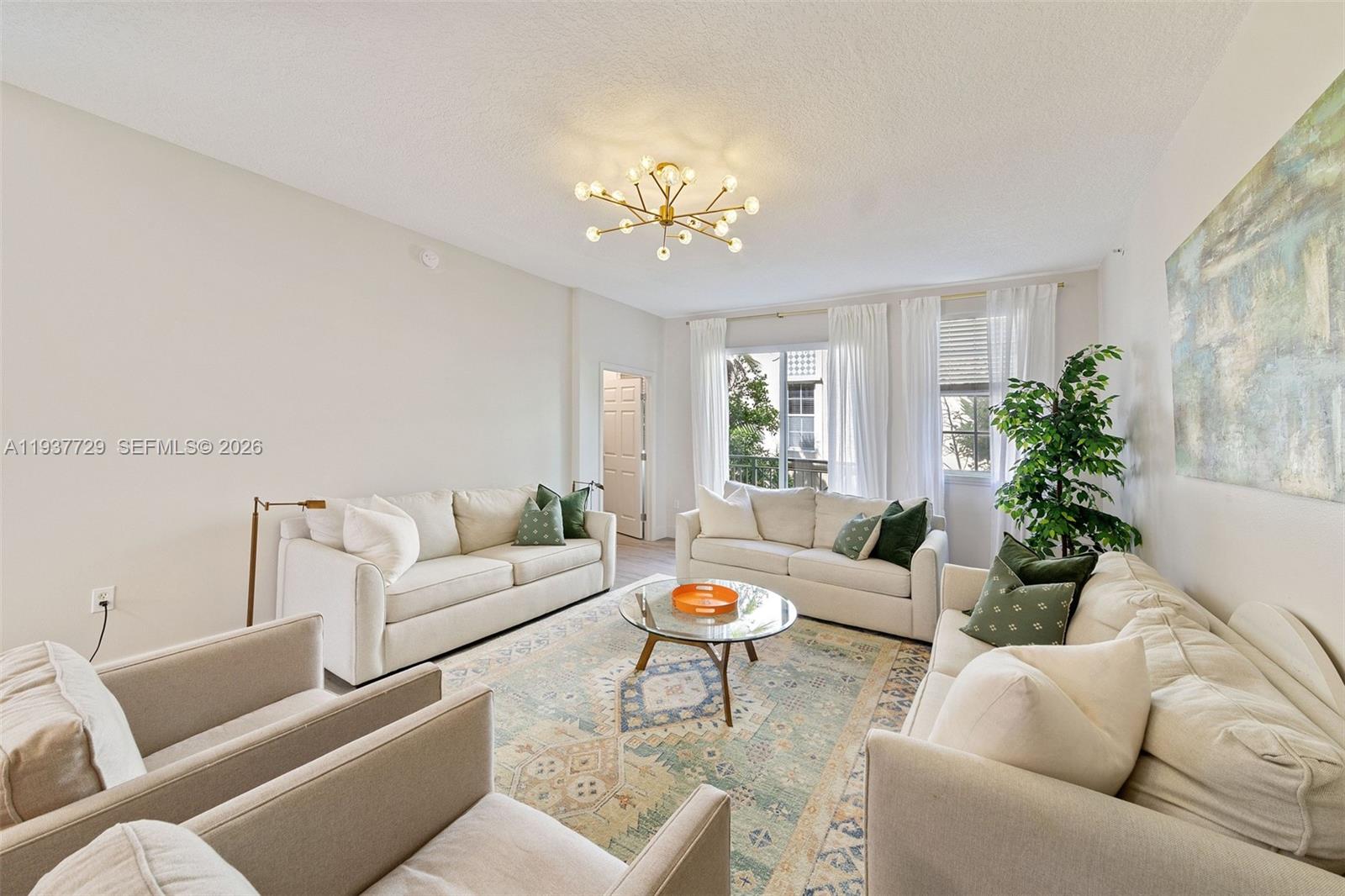 A living room features three light-colored sofas, two armchairs, a glass coffee table, and a chandelier — 2067 S Ocean Dr, Hallandale Beach FL 33009, HALLANDALE BEACH, FL