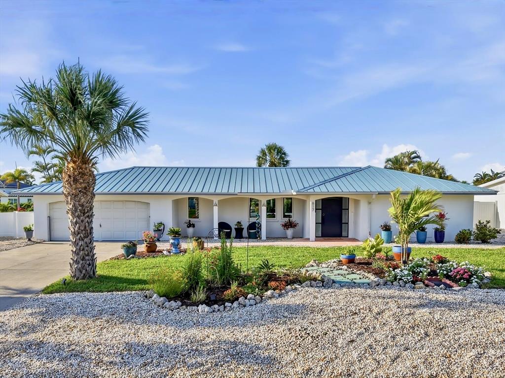 A single-story house with a blue metal roof, white stucco exterior, and a palm tree — 617 DUNDEE LANE, HOLMES BEACH, FL