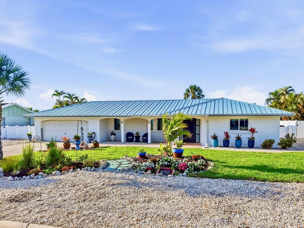 A single-story house with a metal roof, white exterior, and a landscaped front yard — 617 DUNDEE LANE, HOLMES BEACH, FL