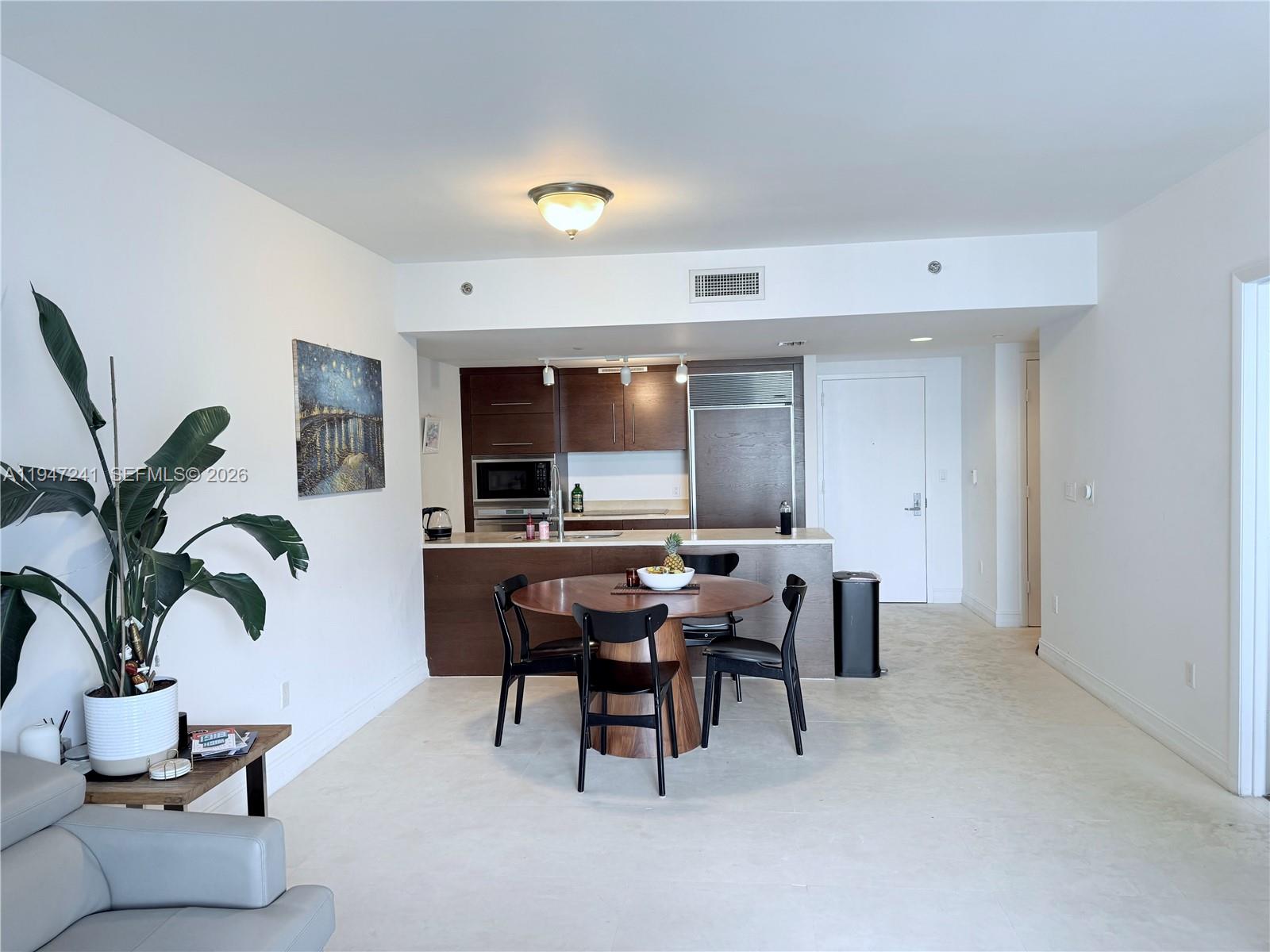 A dining area with a round table sits in front of an open kitchen — 465 Brickell Ave # 2906, Miami FL 33131, MIAMI, FL