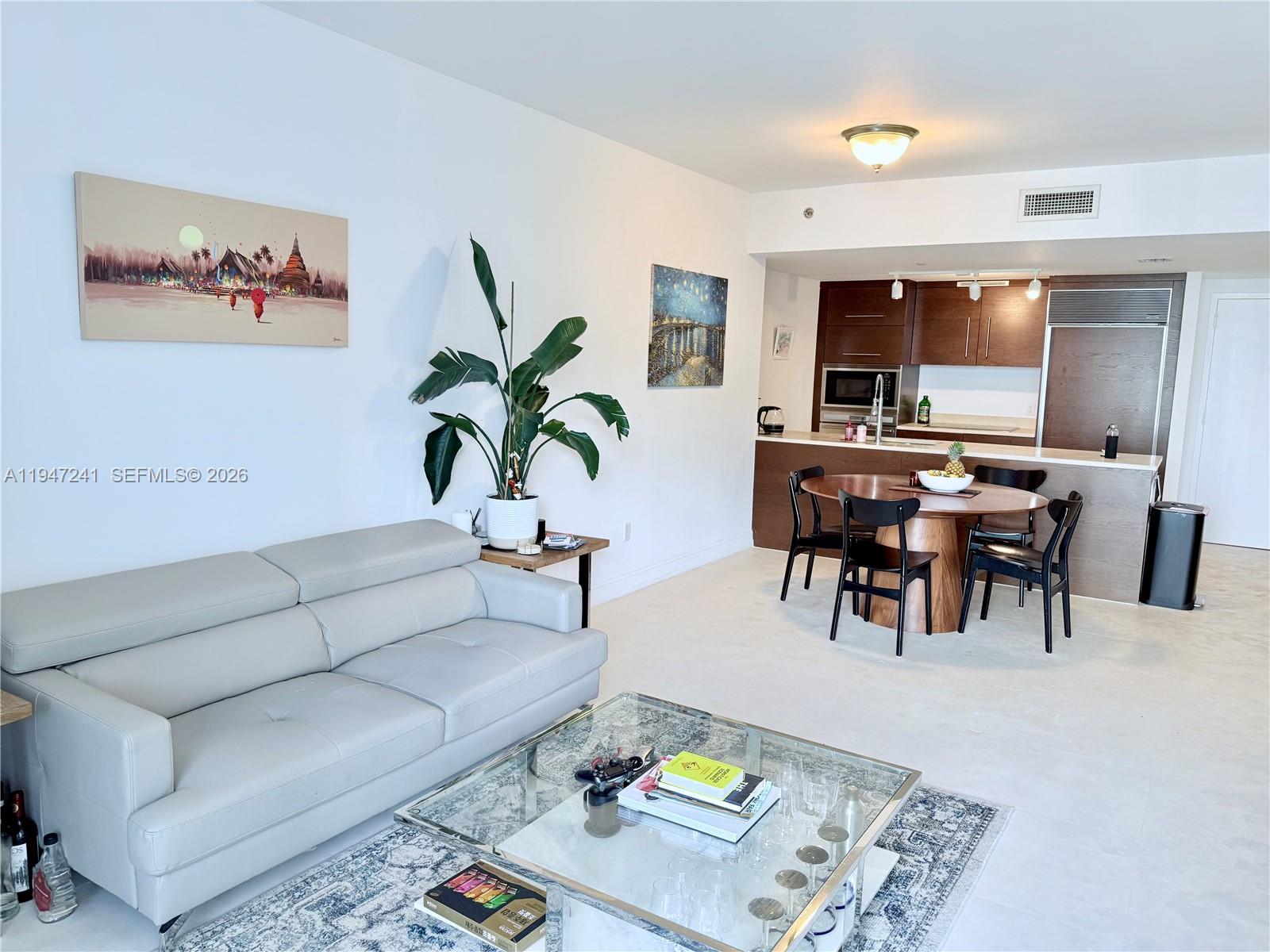 A living room with a light gray sofa and a dining area with dark wood cabinets — 465 Brickell Ave # 2906, Miami FL 33131, MIAMI, FL