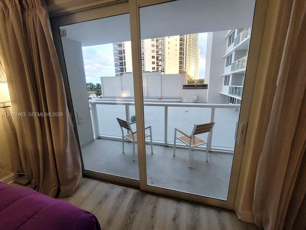 A bedroom with a purple bed and sliding glass doors opening to a balcony — SUNNY ISLES BEACH, FL