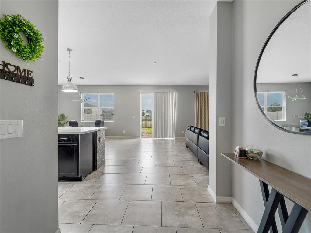 An open-concept living area features tile flooring, a kitchen island, and a sliding glass door — 624 SARDINIA CIRCLE, DAVENPORT, FL
