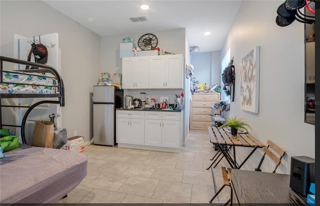 A room with a bunk bed, a small kitchenette with white cabinets, and a dining table — 624 SARDINIA CIRCLE, DAVENPORT, FL