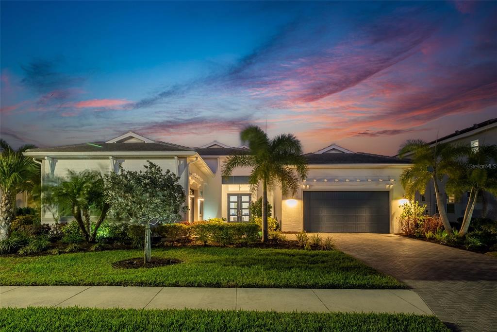 A single-story house with a garage and palm trees under a colorful sunset sky — 8276 REDONDA LOOP, LAKEWOOD RANCH, FL