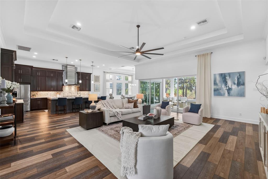 A spacious open-concept living room and kitchen featuring dark wood cabinetry and hardwood flooring — 8276 REDONDA LOOP, LAKEWOOD RANCH, FL