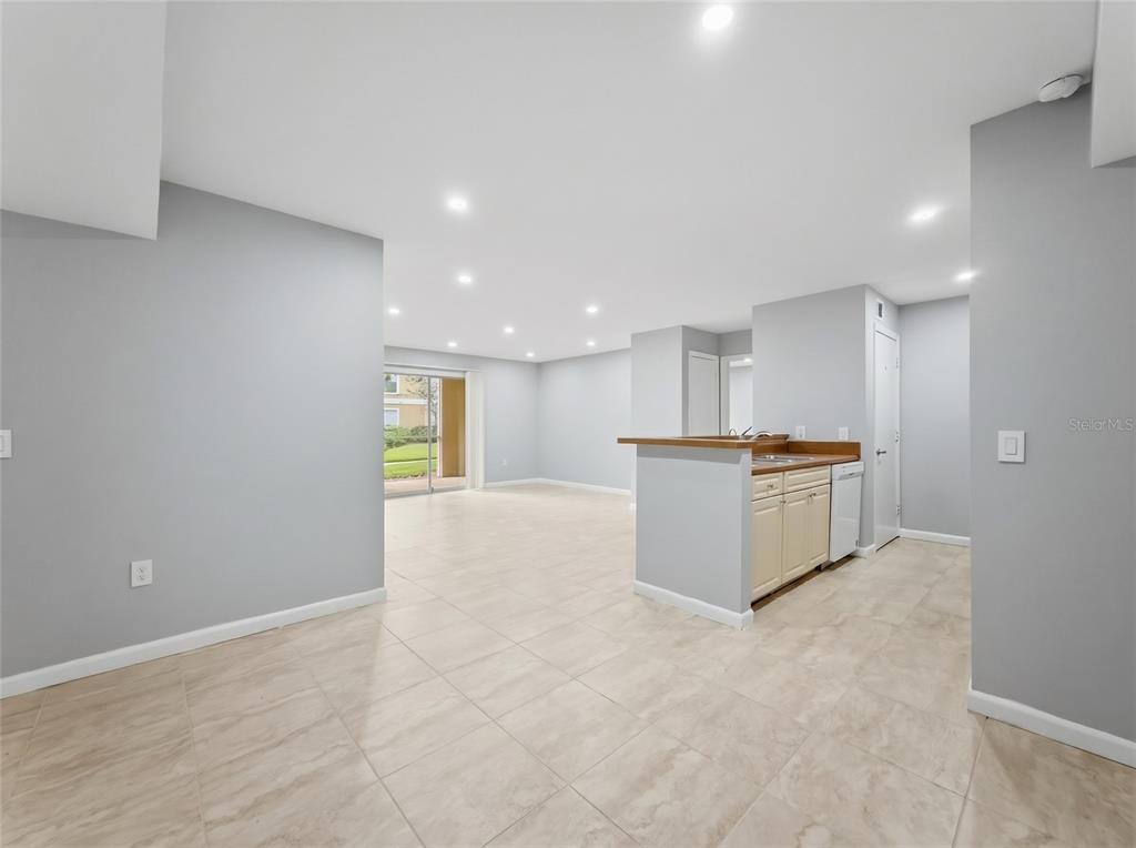 An open-concept living area features light-colored tile flooring, gray walls, and a small kitchen peninsula — 9481 HIGHLAND OAK DRIVE UNIT 1502, TAMPA, FL