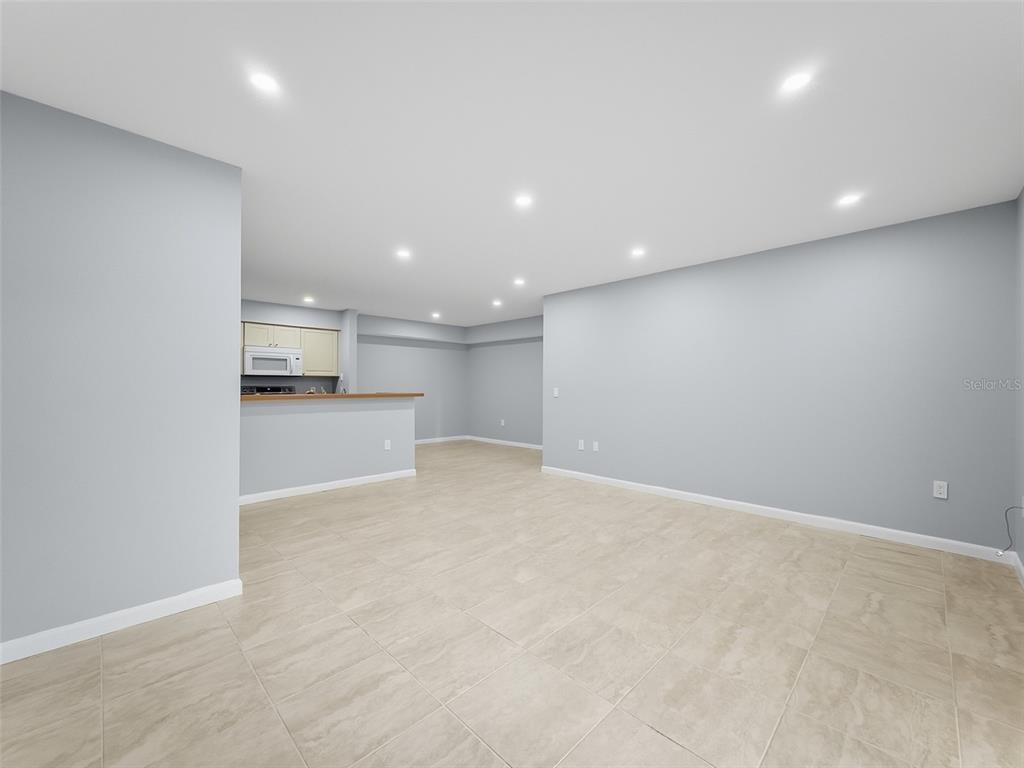 An open-concept living area features light gray walls, recessed lighting, and large beige floor tiles — 9481 HIGHLAND OAK DRIVE UNIT 1502, TAMPA, FL
