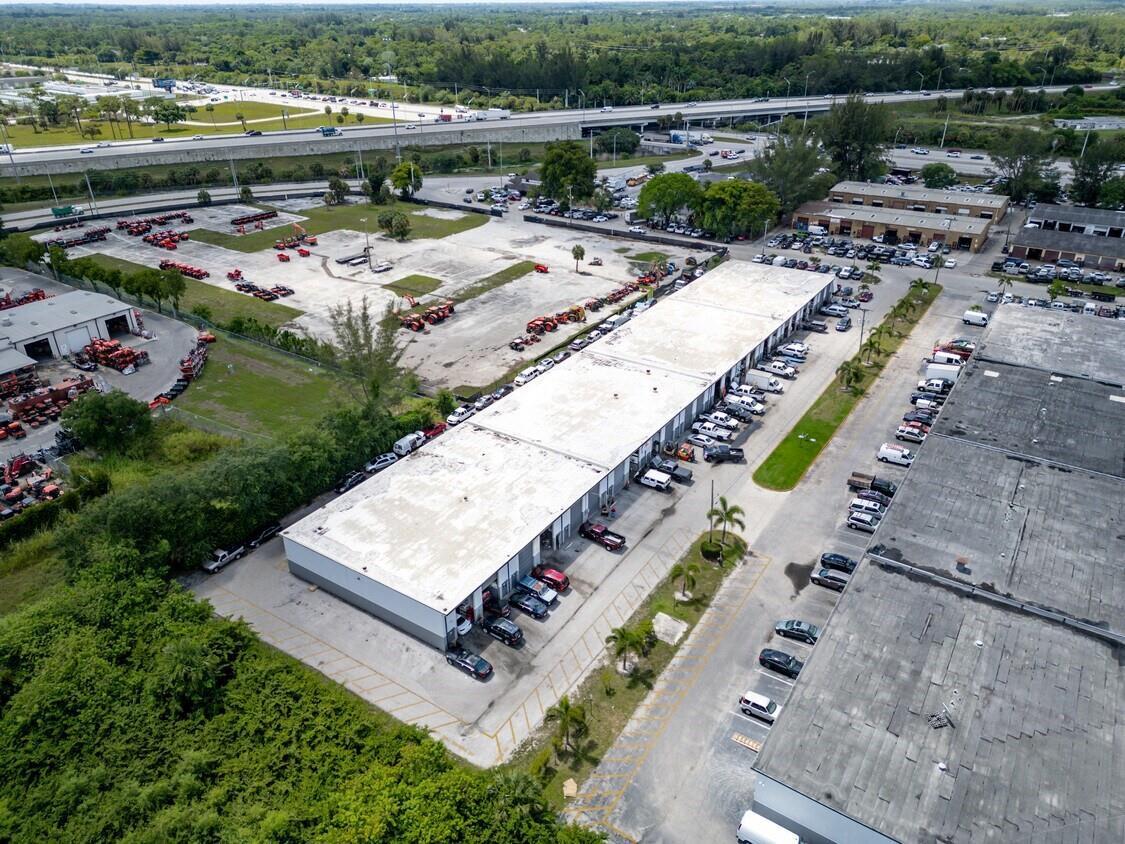 An aerial view shows a long commercial warehouse building with adjacent parking and equipment storage — 7641 Hooper Road, West Palm Beach FL 33411, WEST PALM BEACH, FL
