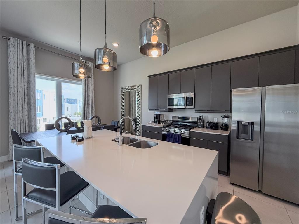 A modern kitchen features a large white island, dark cabinetry, and stainless steel appliances — 7770 SANDY RIDGE DRIVE UNIT 231, REUNION, FL