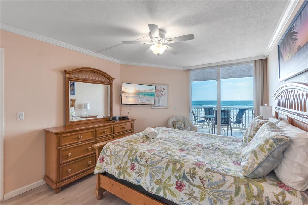 A bedroom with a floral bedspread, wooden furniture, and a balcony overlooking the ocean — 2600 GULF DRIVE N UNIT 12, BRADENTON BEACH, FL