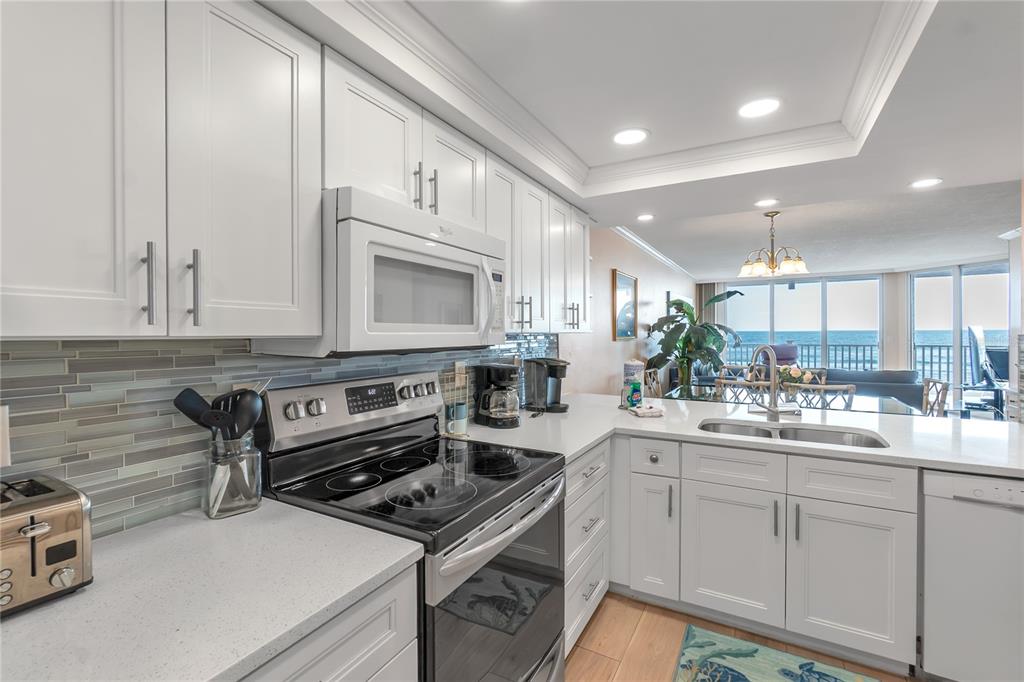 A white kitchen with quartz countertops, stainless steel appliances, and a view of the ocean — 2600 GULF DRIVE N UNIT 12, BRADENTON BEACH, FL
