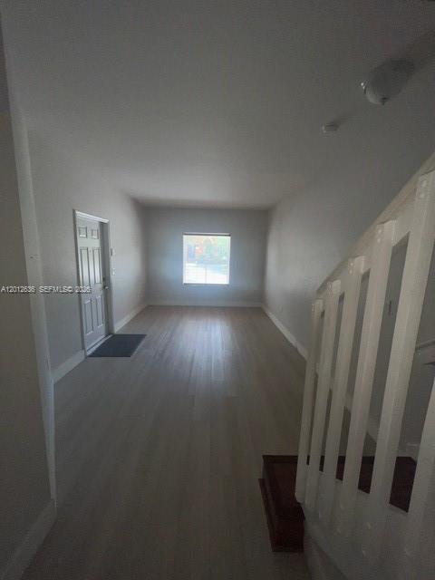 An empty room with light wood flooring, a white door, and a staircase with white railings — 2573 SW 121st Ter # 2003, Miramar FL 33025, MIRAMAR, FL