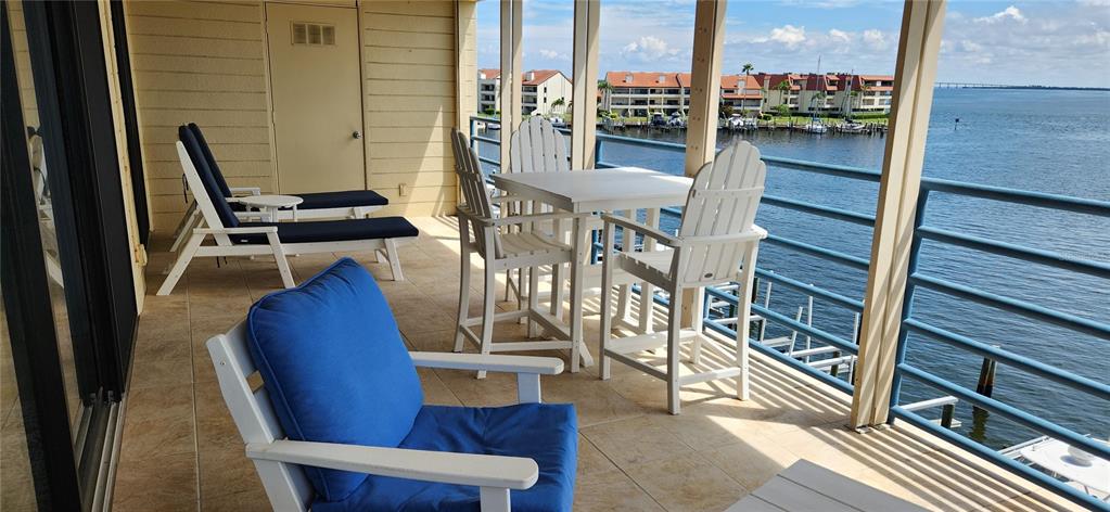 A balcony features outdoor furniture, tile flooring, and a view of a marina and water — 363 PINELLAS BAYWAY S UNIT 50, TIERRA VERDE, FL