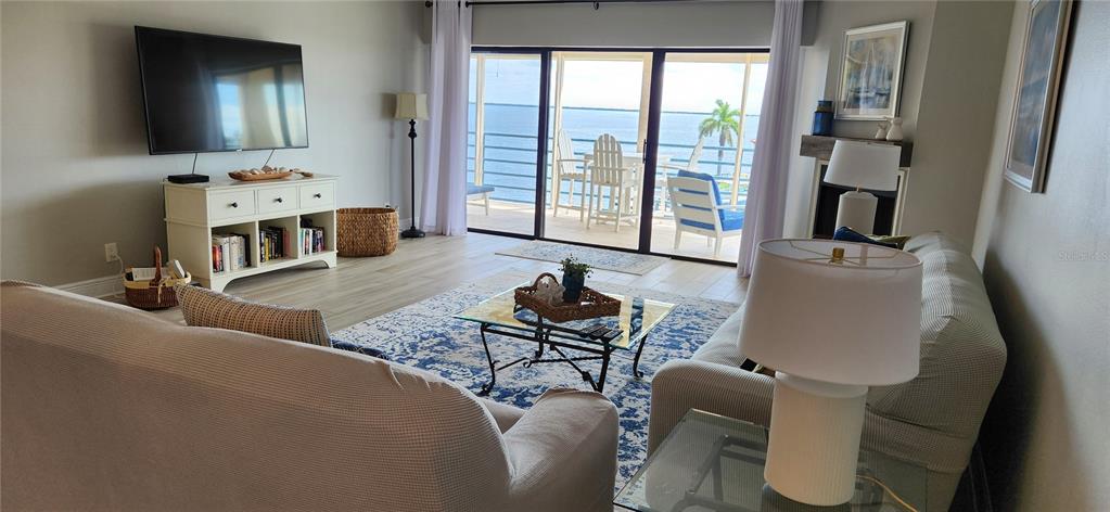 A living room features a television, sofas, a coffee table, and a balcony overlooking water — 363 PINELLAS BAYWAY S UNIT 50, TIERRA VERDE, FL