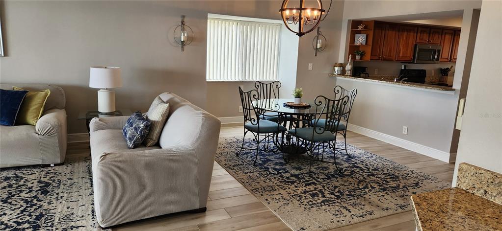 An open-concept living and dining area features a sofa, a round table, and a kitchen — 363 PINELLAS BAYWAY S UNIT 50, TIERRA VERDE, FL