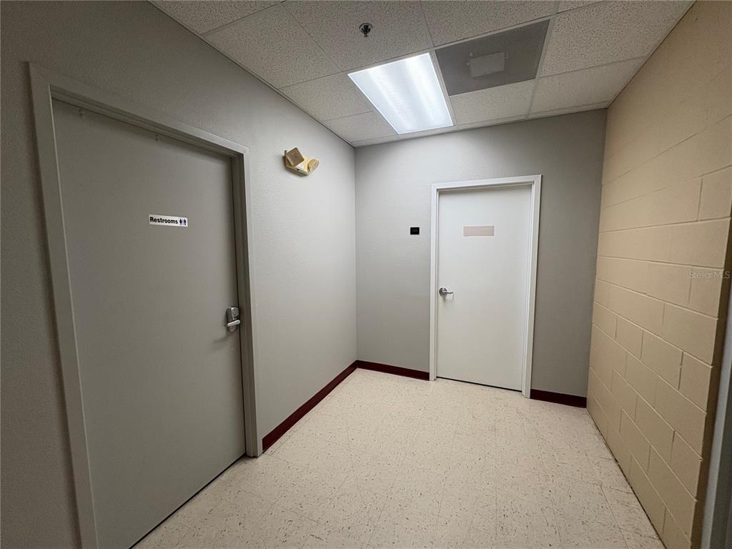 A hallway with two doors, a drop ceiling, and a beige block wall — 13250 N 56TH STREET UNIT 103, TEMPLE TERRACE, FL