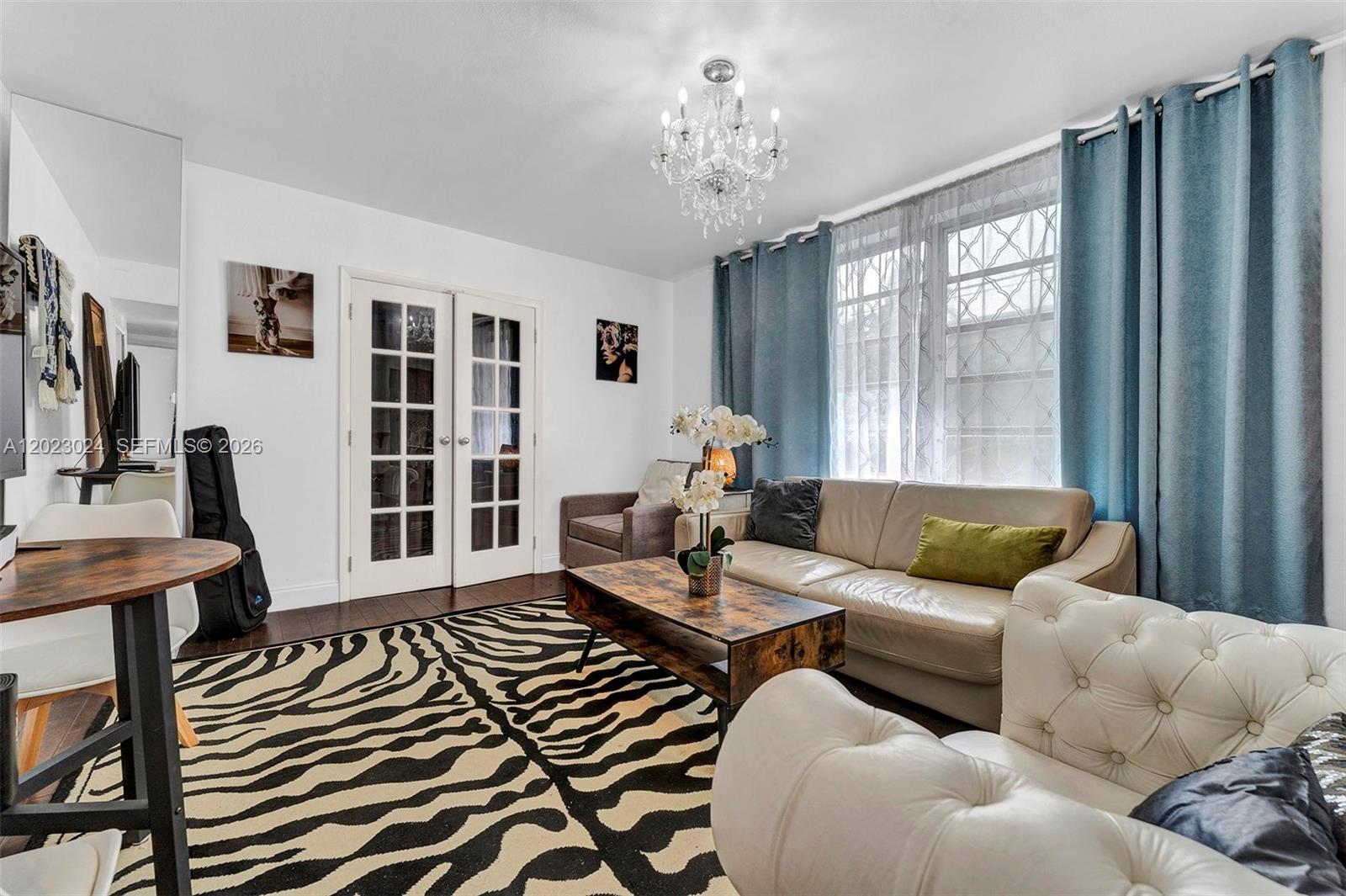 A living room features a zebra-print rug, a beige sofa, and a crystal chandelier — 1150 Euclid Ave # 101, Miami Beach FL 33139, MIAMI BEACH, FL