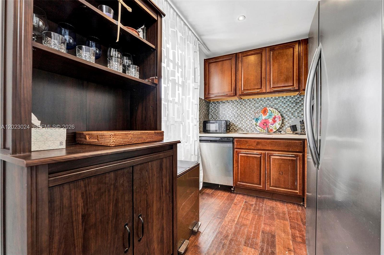 A small kitchen features dark wood cabinets, stainless steel appliances, and a wooden hutch — 1150 Euclid Ave # 101, Miami Beach FL 33139, MIAMI BEACH, FL