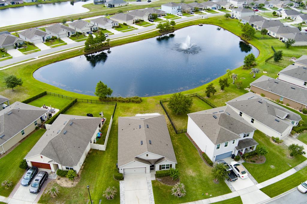An aerial view shows suburban houses surrounding a large pond with a central water fountain — 1814 PALMETTO SCRUB CIRCLE, PORT ORANGE, FL