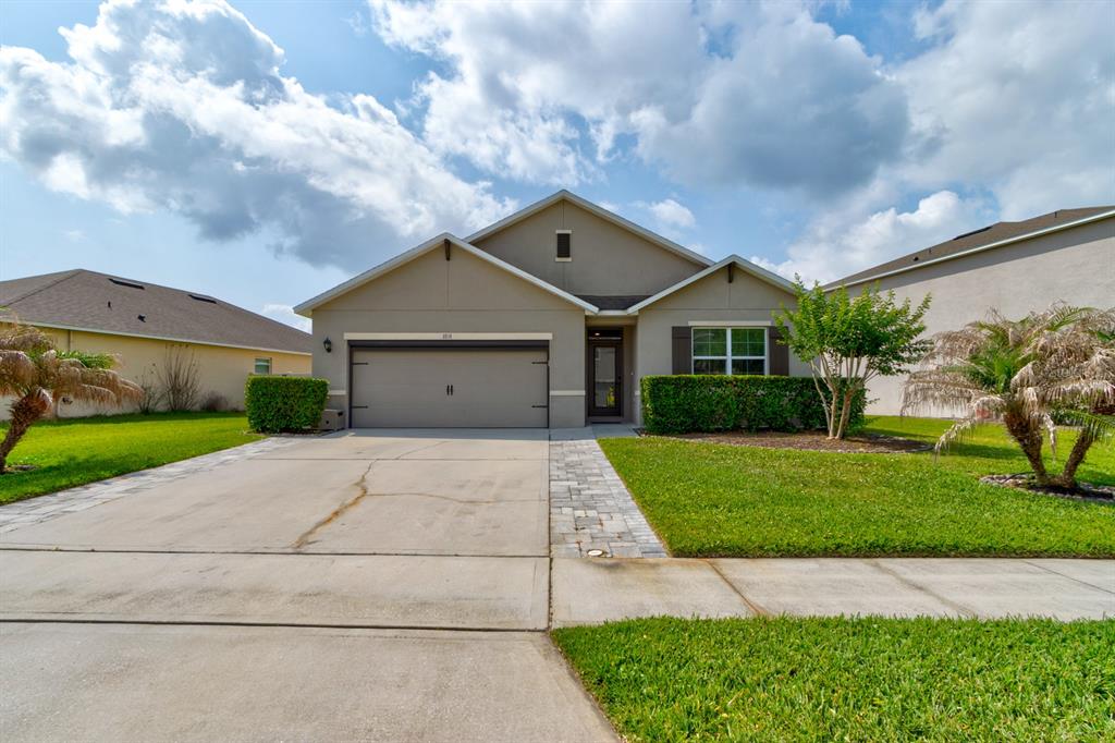 A single-story suburban house features a two-car garage, a paved walkway, and a front lawn — 1814 PALMETTO SCRUB CIRCLE, PORT ORANGE, FL