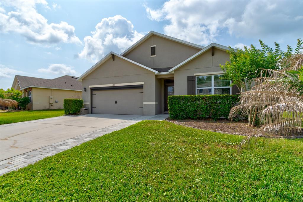 A beige single-story house features a two-car garage, a front lawn, and a paved driveway — 1814 PALMETTO SCRUB CIRCLE, PORT ORANGE, FL