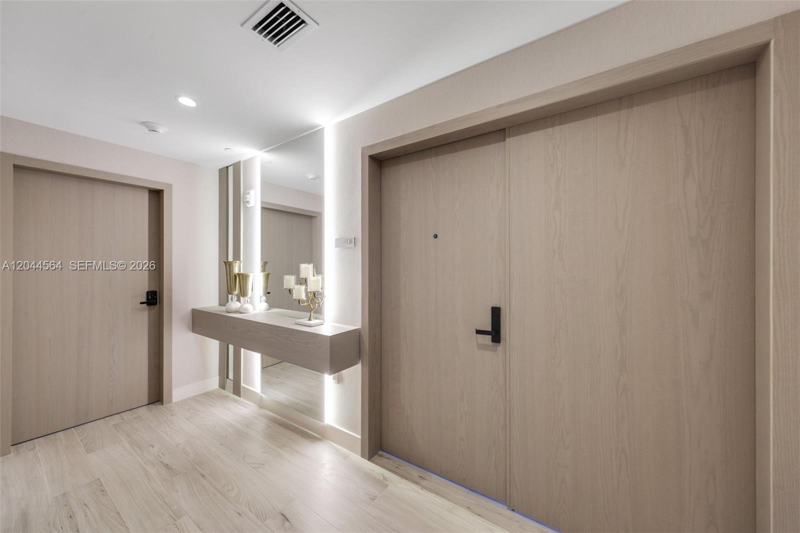 A modern entryway features light wood doors, a floating console table, and a backlit mirror — 700 NE 24th Street # 1401, Miami FL 33137, MIAMI, FL
