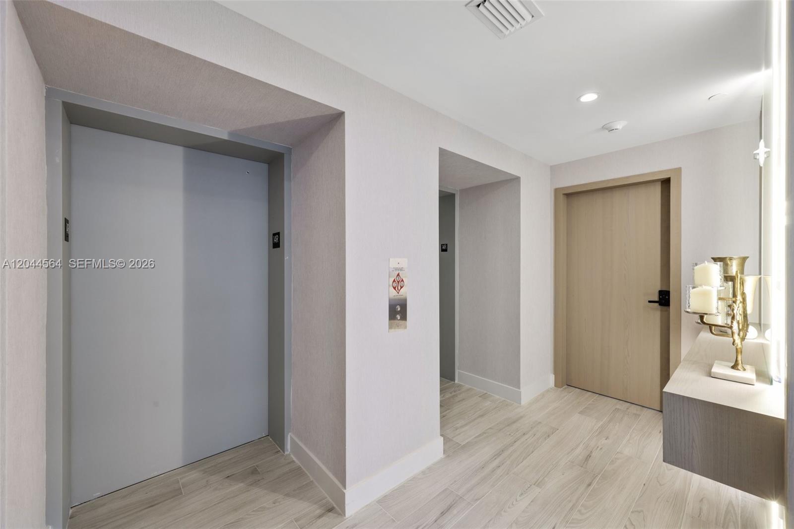 A hallway features two elevator doors, a wooden door, and a decorative candle holder — 700 NE 24th Street # 1401, Miami FL 33137, MIAMI, FL