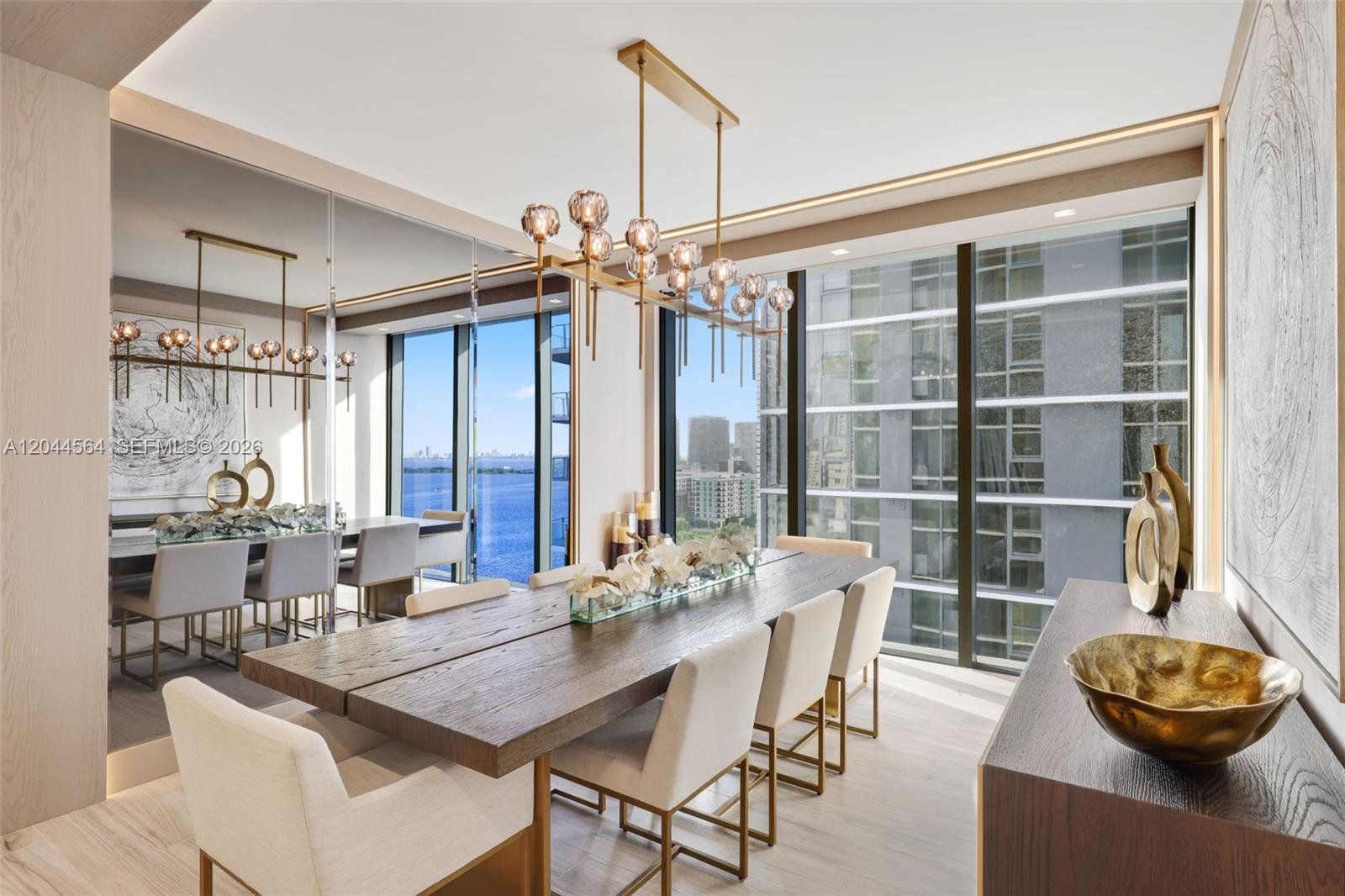 A modern dining room features a long wooden table, upholstered chairs, and floor-to-ceiling windows — 700 NE 24th Street # 1401, Miami FL 33137, MIAMI, FL