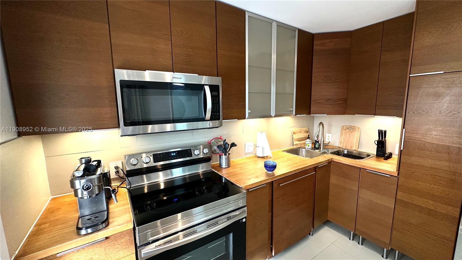 A kitchen features wood-grain cabinets, stainless steel appliances, and light-colored wooden countertops — 2651 S Course Dr # 307, Pompano Beach FL 33069, POMPANO BEACH, FL