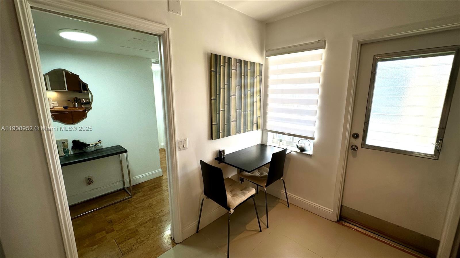 A small dining area features a black table, two chairs, and bamboo wall art — 2651 S Course Dr # 307, Pompano Beach FL 33069, POMPANO BEACH, FL