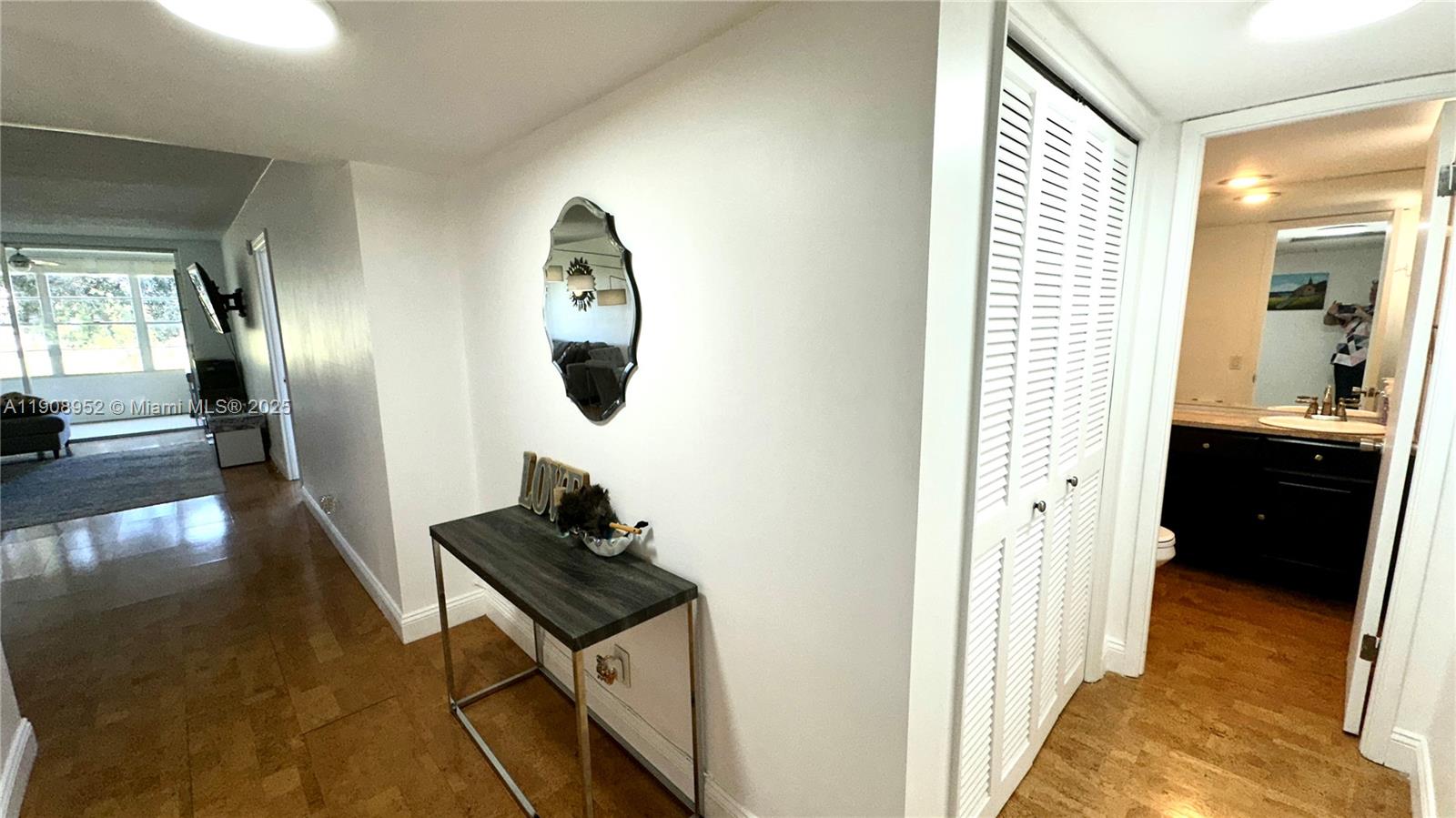 A hallway features a console table, a wall mirror, and a louvered closet door — 2651 S Course Dr # 307, Pompano Beach FL 33069, POMPANO BEACH, FL