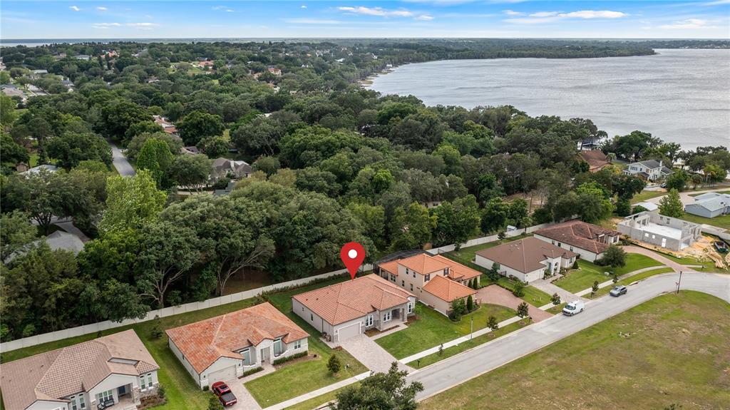 An aerial view shows a suburban neighborhood with houses featuring red tile roofs near water — 12919 BRUNELLO CIRCLE, CLERMONT, FL