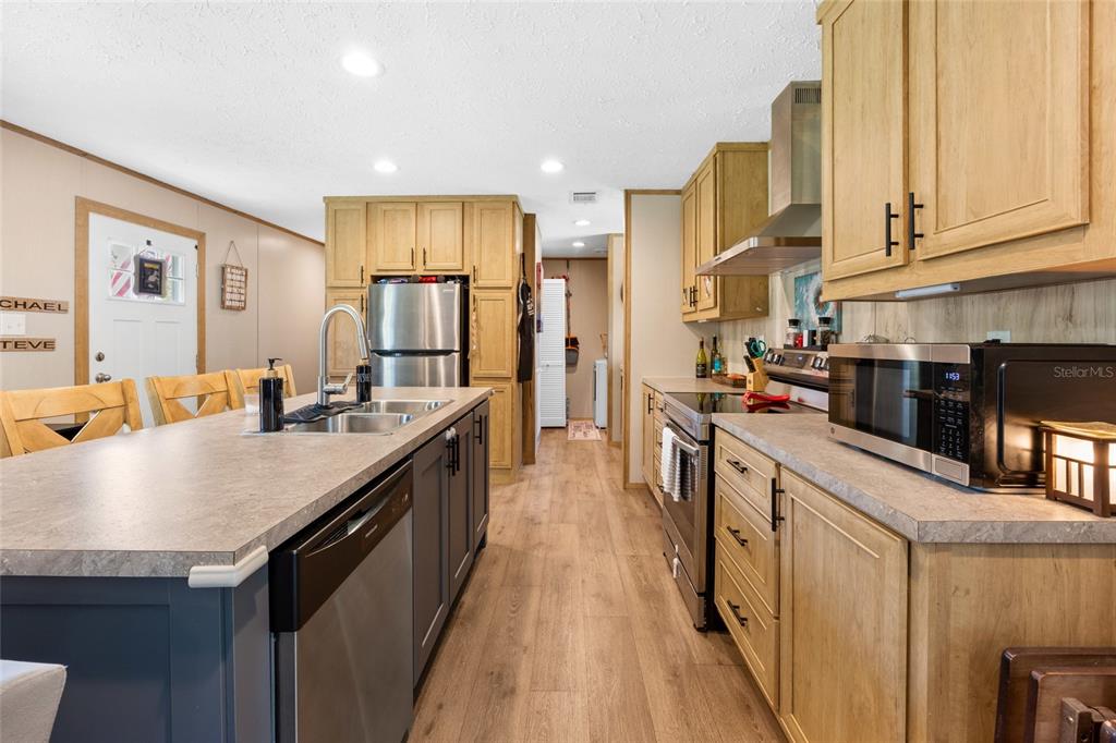 A kitchen features light wood cabinets, a gray island with a dishwasher, and stainless appliances — 8444 W JENNIFER COURT, CRYSTAL RIVER, FL