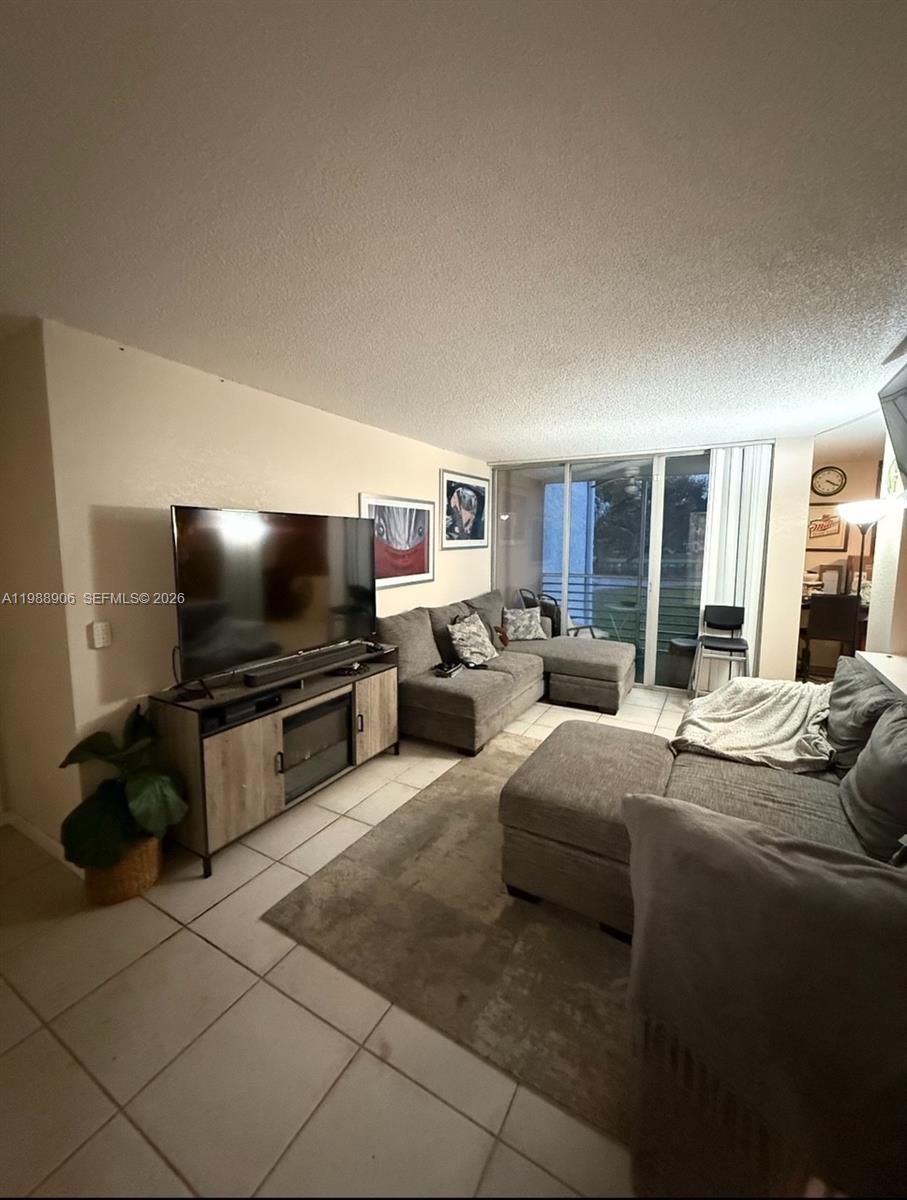 An empty room features light-colored tile flooring, white walls, and a pass-through kitchen window — 9441 Live Oak Pl # 209, Davie FL 33324, DAVIE, FL