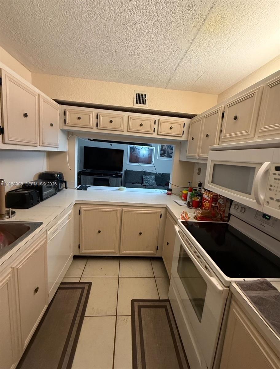 A living room with beige tile flooring, white walls, and a sliding glass door — 9441 Live Oak Pl # 209, Davie FL 33324, DAVIE, FL