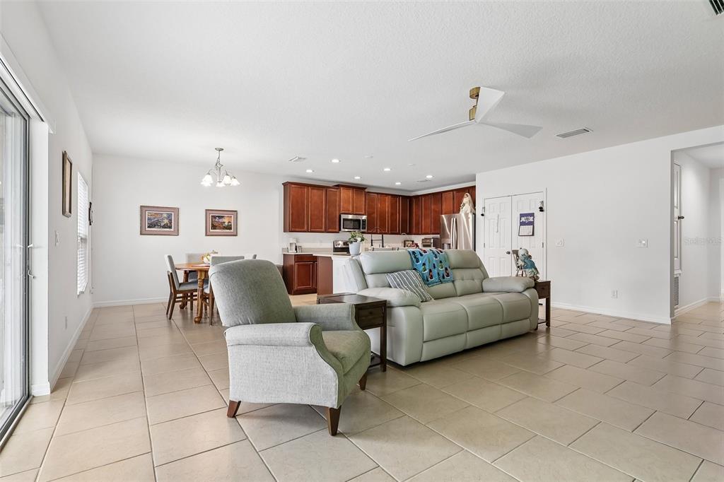 An open-concept living and dining area features tile flooring, a light-colored sofa, and wood cabinetry — 833 AVENAL LANE, DAVENPORT, FL