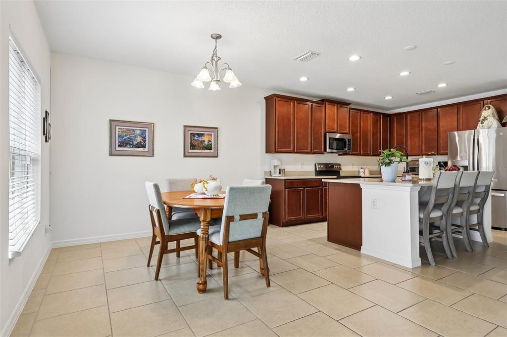 A kitchen with dark wood cabinets and a dining area with a round wooden table — 833 AVENAL LANE, DAVENPORT, FL